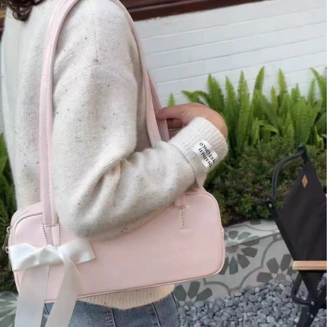 Rosalie pink bow shoulder bag worn with a cream knit